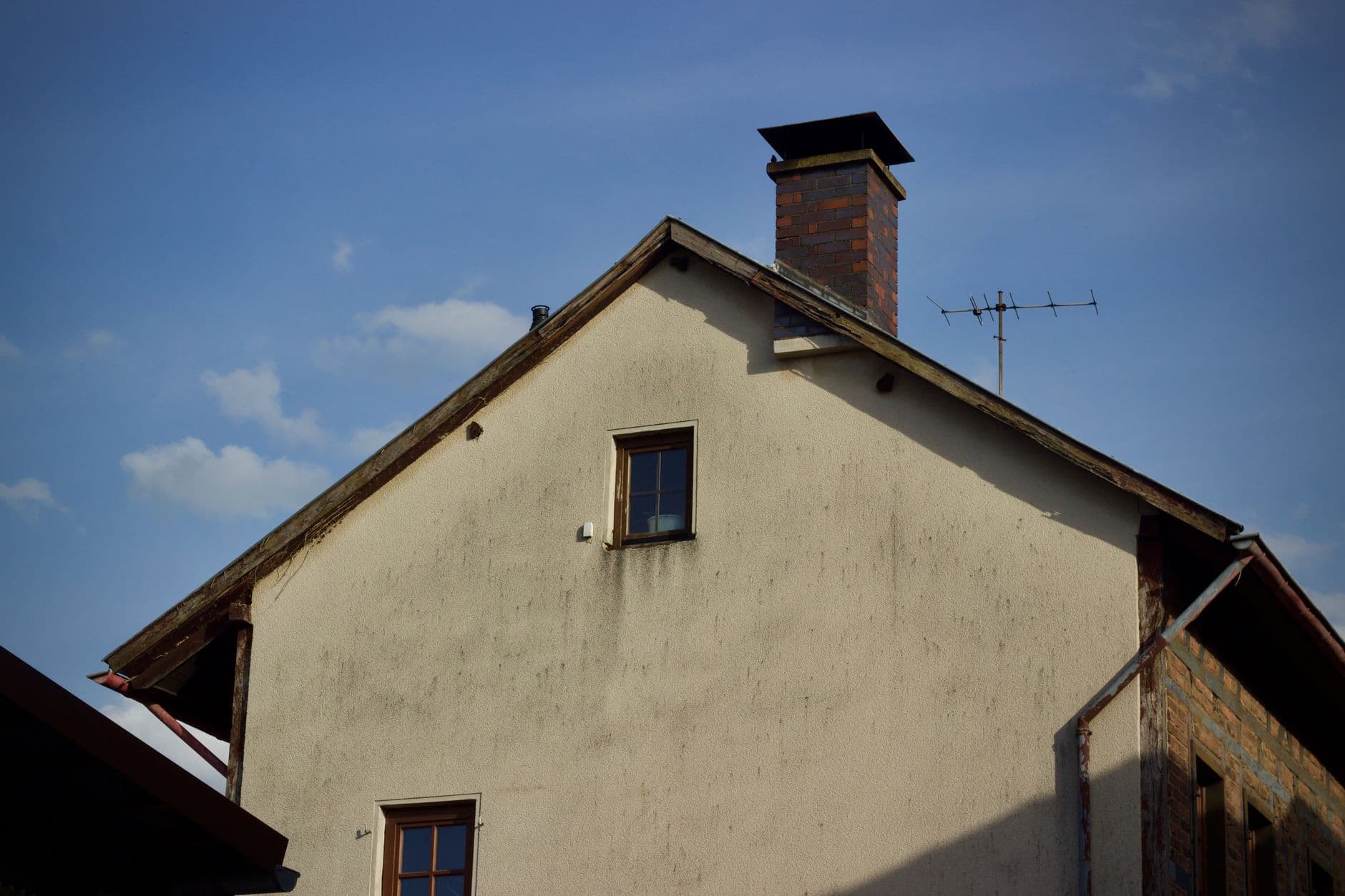 A rustic house exterior with a brick chimney set against a clear blue sky.